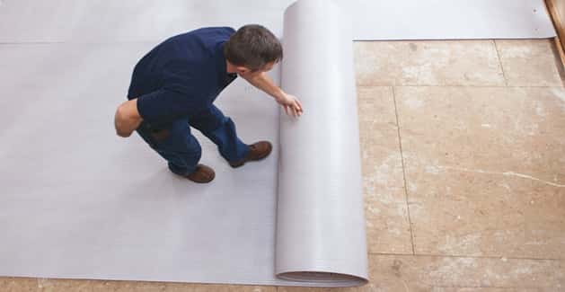 flooring installer rolls out carpet padding on top of subfloor